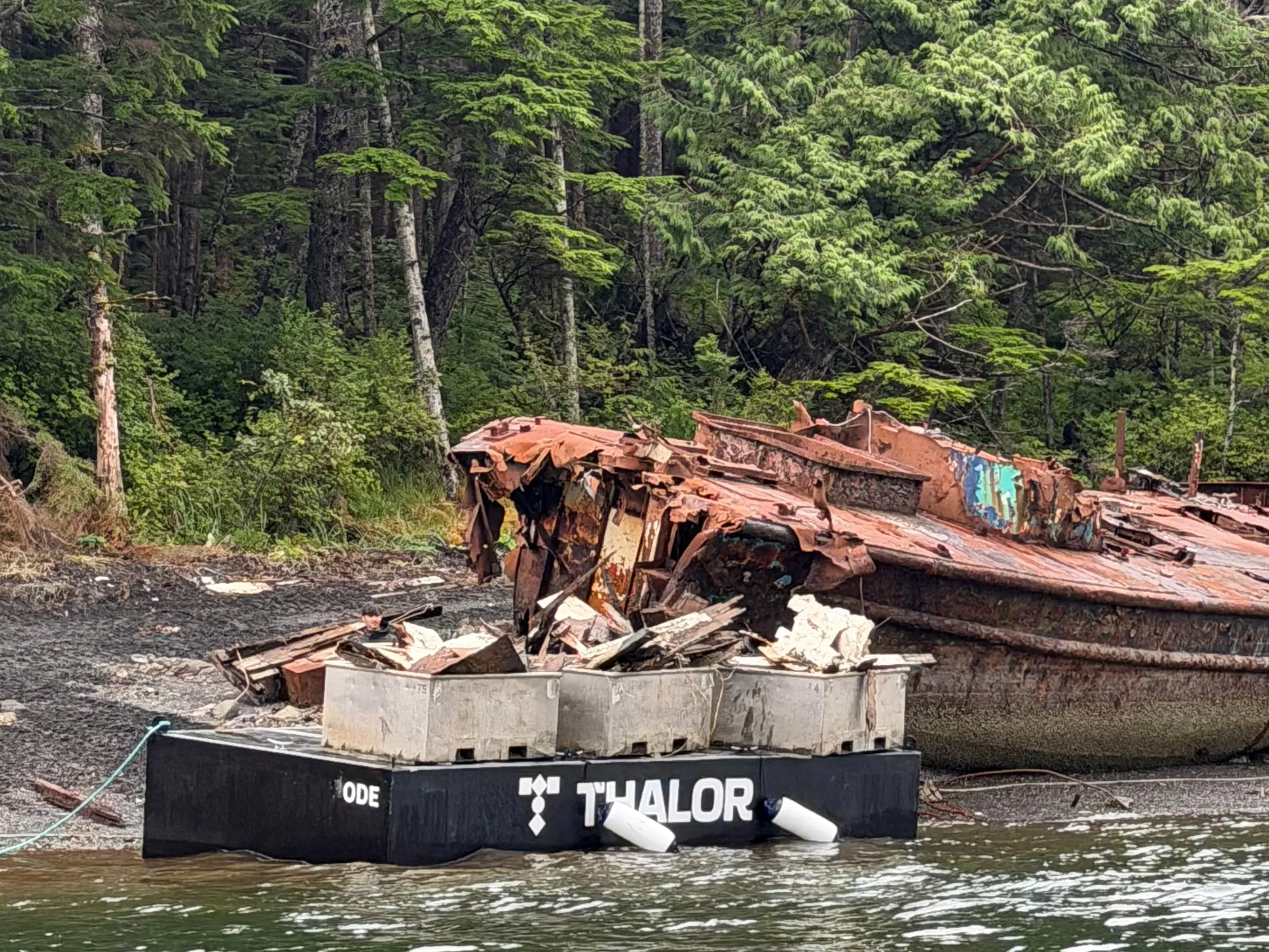 ODE-001 loaded with debris bins beside a dismantled vessel during cleanup in Metlakatla.